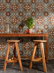 Przy ścianie drewniany stół i dwa krzesła, na podłodze grafitowe płytki, ściana wyłożona Peronda FS Barna Born 45x45 płytka patchworkowa