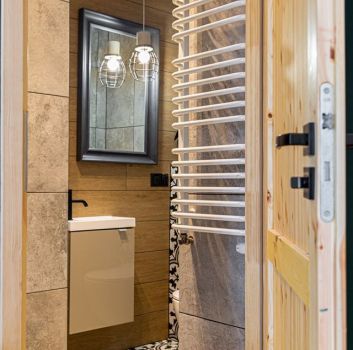 Beżowa toaleta z beżową szafką z wbudowaną umywalką, prostokątnym lustrem oraz toaletą