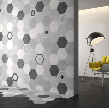 Szary pokój z limonkowym fotelem oraz czarną lampą oraz przejściem do pokoju w którym jest ściana z płytkami heksagonalnymi