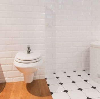 Biało-czarna łazienka z toaletą, bidetem i zabudowaną wanną