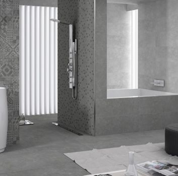 Szara łazienka z wbudowaną wanną, dużym pionowym grzejnikiem oraz umywalką wolnostojącą w kształcie tuby