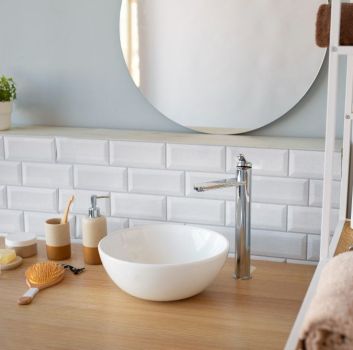 Ściana w łazience wyłożona białymi cegiełkami z drewnianym blatem z okrągłą umywalką i lustrem
