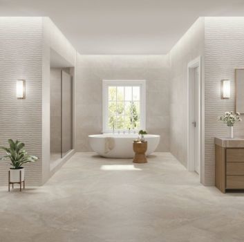 Duża, przestronna łazienka wyłożona beżowymi płytkami imitującymi kamień z kolekcji Lucca, z białą wanną wolnostojącą, kabiną przysznicową, szafką z umywalką, dużym lustrem i drabiną z ręcznikiem