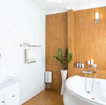 Biała łazienka z elementami drewna, z wanną narożną i szafką z umywalką oraz dużym lustrem