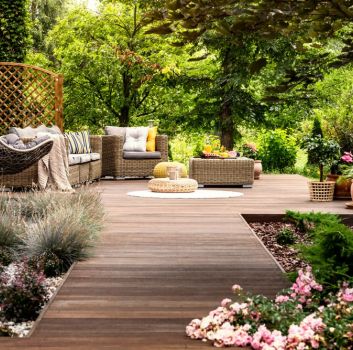 Piękny ogród z drewnianym tarasem ze strefą relaksu i meblami wypoczynkowymi