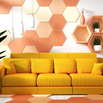 Kolorowy salon z żółtą kanapą, kwiatem w donicy, lampą wiszącą, ścianą i podłogą wyłożoną kolorowymi płytkami heksagonalnymi oraz półkami heksagonalnymi z roślinami i dzbanami