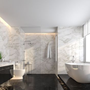 Łazienka wyłożona czarnymi i białymi płytkami imitującymi marmur, z kabiną prysznicową, wanną wolnostojącą, wiszącą szafką z umywalką, okrągłym lustrem i miską WC