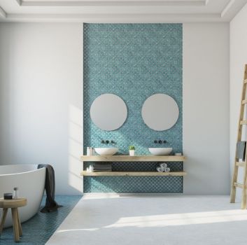 Biała łazienka z niebieską mozaiką na fragmentach ściany, z białą wanną wolnostojącą, drewnianą półką wiszącą z dwiema umywalkami nablatowymi, dwoma okrągłymi lustrami i drabiną