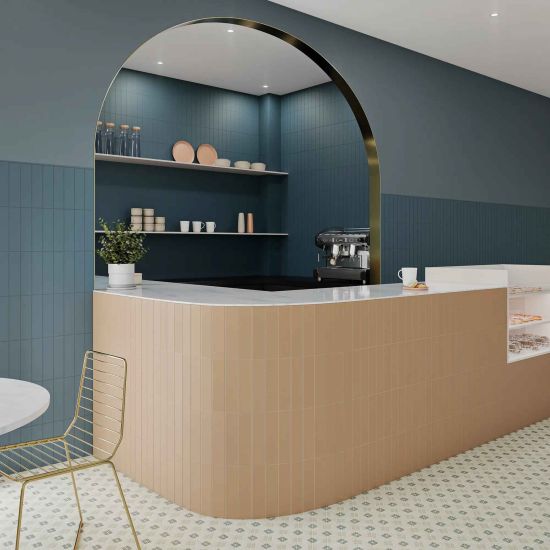 Restauracja ze ścianą wyłożoną niebieskimi cegiełkami bazowymi Texiture Ocean Matt, z p&oacute;łokrągłym barem, gablotą z wypiekami, naczyniami, stolikiem i krzesłem