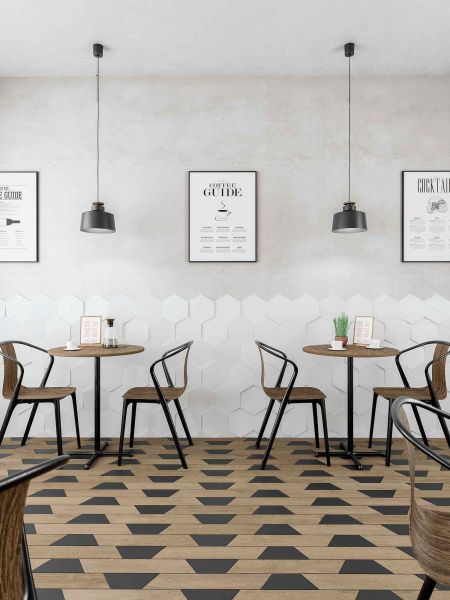 Restauracja z ciemnymi płytkami drewnopodobnymi w jodełkę Chevron A Wood Dark na podłodze z czarnymi płytkami trapezowymi, z okrągłymi stolikami, krzesłami i lampami wiszącymi