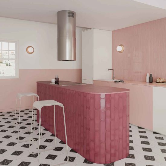 Kolorowa kuchnia z jedną ścianą wyłożoną r&oacute;żowymi cegiełkami Grace Blush Gloss, z białymi i r&oacute;żowymi meblami, wyspą i dwoma białymi taboretami