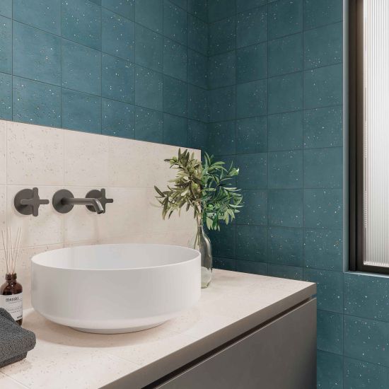 Łazienka z blatem i ścianką przy umywalce nablatowej wyłożonymi białymi płytkami dekoracyjnymi Stardust Pebbels Ivory, z baterią podtynkową