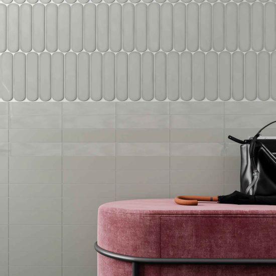 Zbliżenie na ścianę wyłożoną szarymi cegiełkami Grace Grey Gloss, z r&oacute;żową pufą z parasolem i czarną torebką