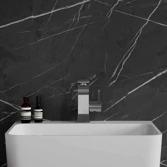 Widok od przodu na białą umywalkę z baterią stojącą w chromie Omnires Darling na tle ciemnej, kamiennej ściany