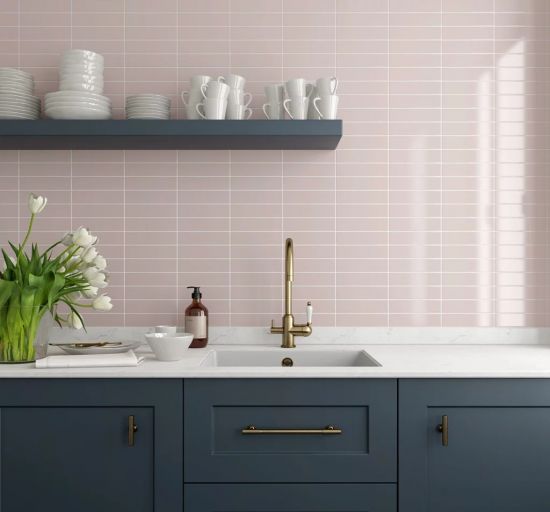 Ściana w kuchni wyłożona jasnor&oacute;żowymi cegiełkami w połysku Costa Nova Pink Stony Gloss z granatowymi meblami i p&oacute;łką wiszącą z naczyniami
