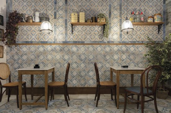 Restauracja z dwoma stolikami, czterema krzesłami, wiszącymi p&oacute;łkami na ścianie, kwiatami i płytkami z kolekcji FS Roots