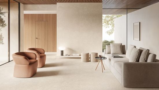 Wizualizacja minimalistycznego salonu w ciepłych beżach. Na wielkoformatowych płytkach podłogowych stoi szara sofa, mały stolik i dwa sk&oacute;rzane fotele w odcieniu terakoty. W tle widać drewniane i kamienne okładziny ścienne.