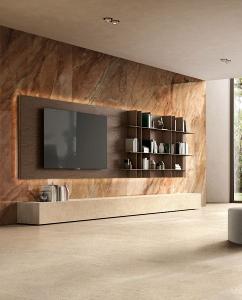 Salon z teleiwzorem i wielkimi płytkami na ścianie imitującymi kamień i beżowymi płytkami na podłodze