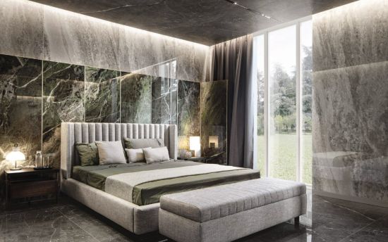 Nowoczesna sypialnia z ł&oacute;żkiem tapicerowanym i ścianą z płyt wielkoformatowych Florim Heritage Luxe Emerald o wzorze ciemnozielonego marmuru. Duże okno z widokiem na ogr&oacute;d i nastrojowe oświetlenie.
