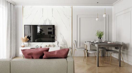 Elegancki salon z jadalnią. Na ścianie TV z białego marmuru, obok szary st&oacute;ł z welurowymi krzesłami na złotych nogach. Ściany zdobi klasyczna sztukateria. Całość w jasnych barwach z akcentem brudnego r&oacute;żu na poduszkach i złotymi dodatkami.