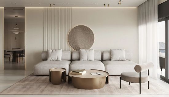 Jasny salon w stylu minimalistycznym. Beżowa kanapa i fotel stoją na dywanie. Na ścianie wiszą pionowe lamele oraz duża, okrągła, podświetlana płaskorzeźba. Z przodu niskie stoliki kawowe.