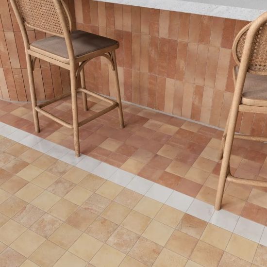 Nowoczesny aneks kuchenny lub bar z podłogą wyłożoną kwadratowymi beżowo-terakotowymi płytkami i pionową ścianą z terakotowych kafelk&oacute;w cegiełek oraz dwoma wiklinowymi hokerami.