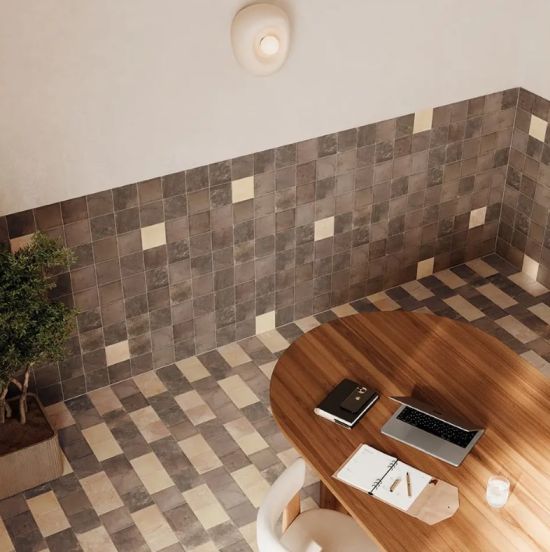 Nowoczesne wnętrze z geometrycznymi płytkami na podłodze i ścianie, drewnianym stołem, białym krzesłem i rośliną doniczkową.