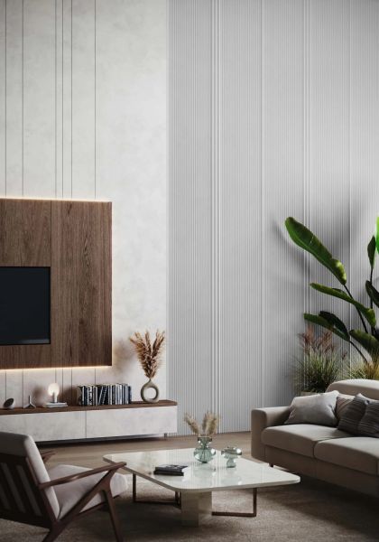Jasny salon ze ścianą z TV w drewnianej obudowie i białymi, wysokimi lamelami. Na dole długa szafka, z boku beżowa sofa z poduszkami, marmurowy stolik i duża roślina. W tle fotel.